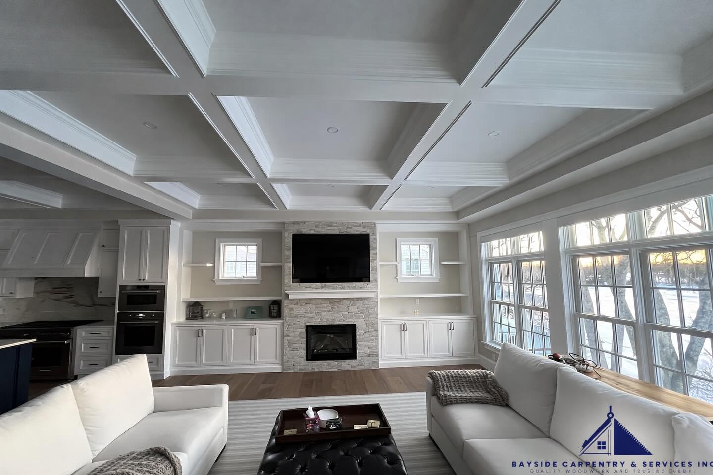 A finished living space with a coffered ceiling, detailed trim and built-in cabinetry.