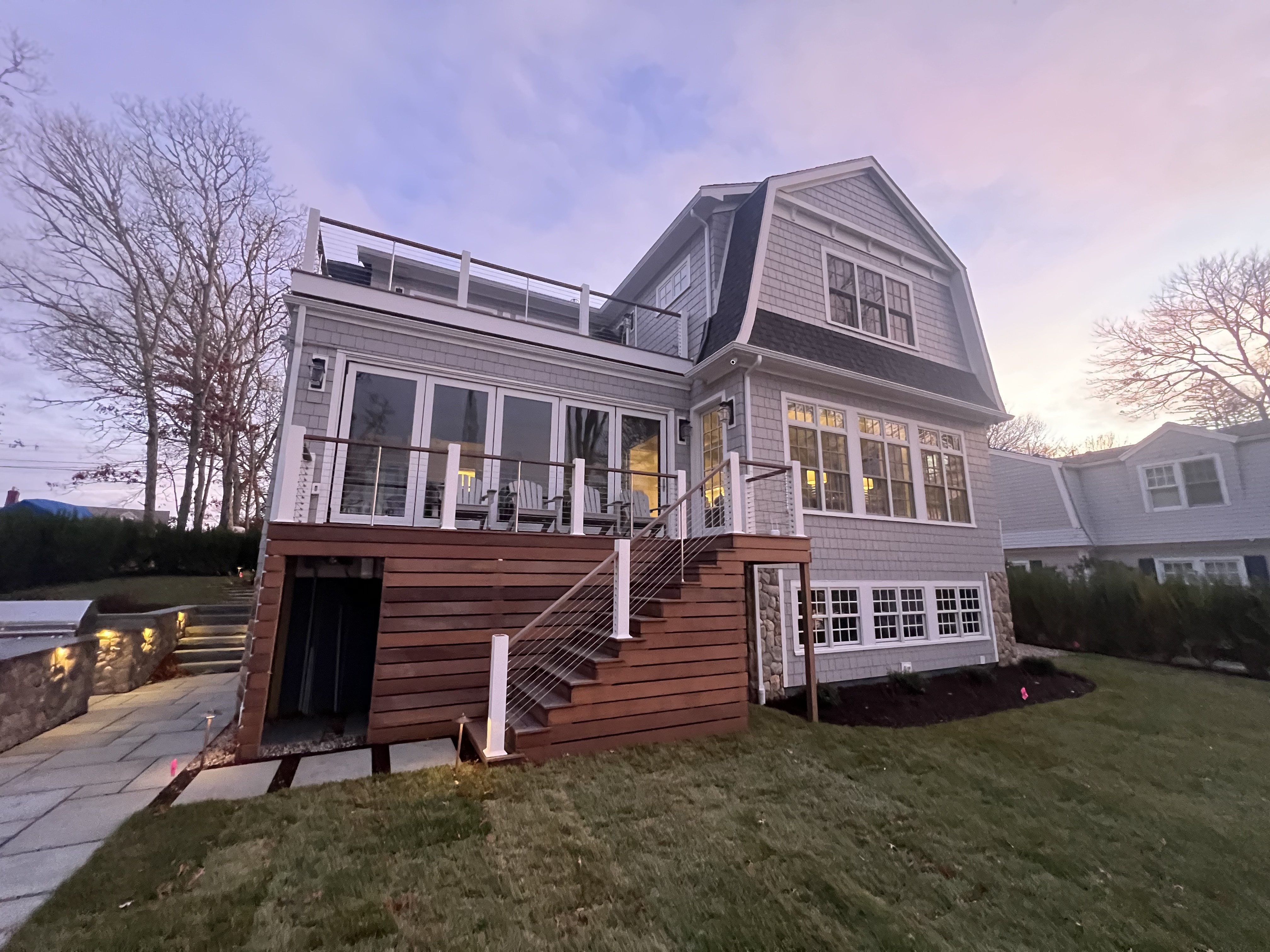 BaySide exterior carpentry with a finished deck, stairs, and railings at dusk